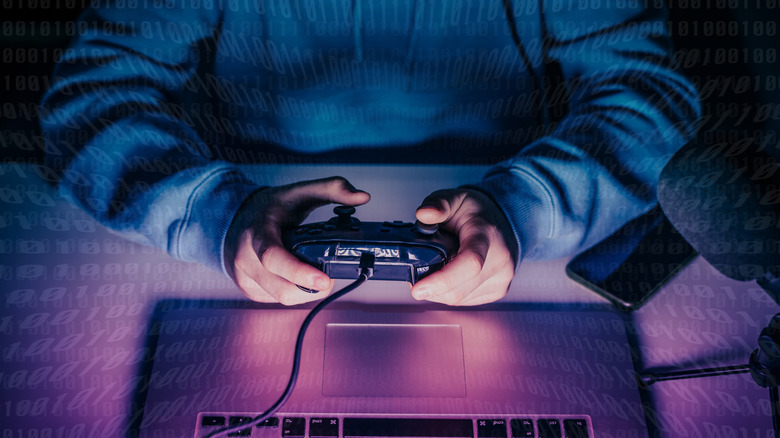 Teen gaming online on his laptop using a controller