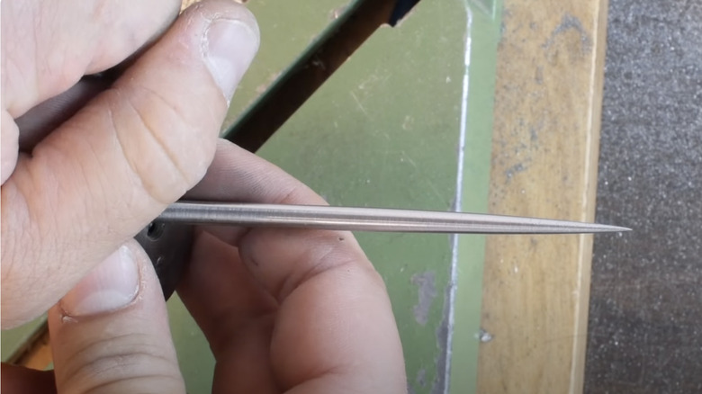 person holding awl made from screwdriver