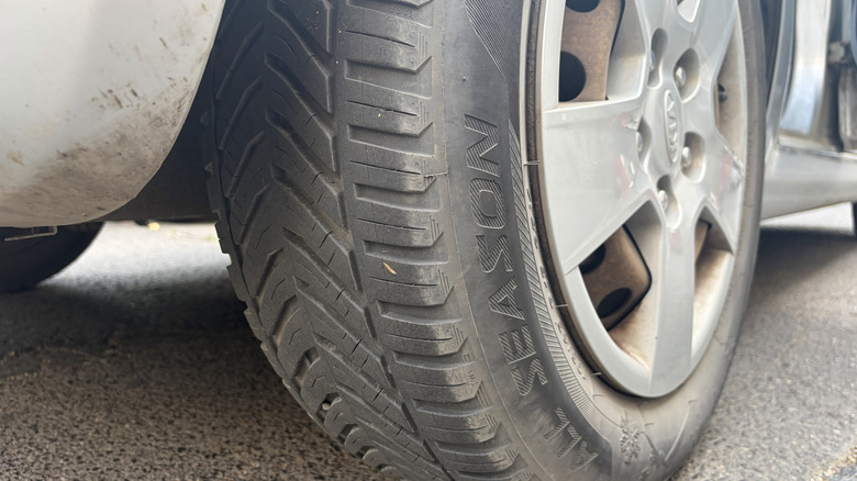 A closeup of an all-season tire on a car