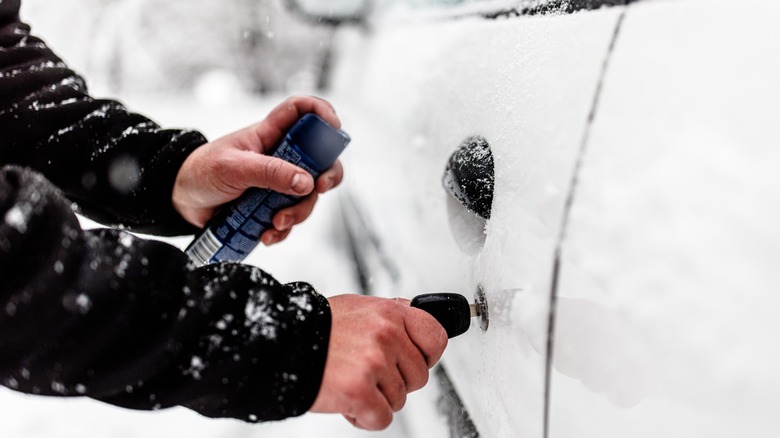 Person trying to unfreeze car door lock using spray