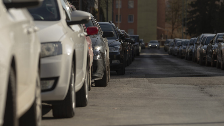 Line of parked vehicles on a busy road.