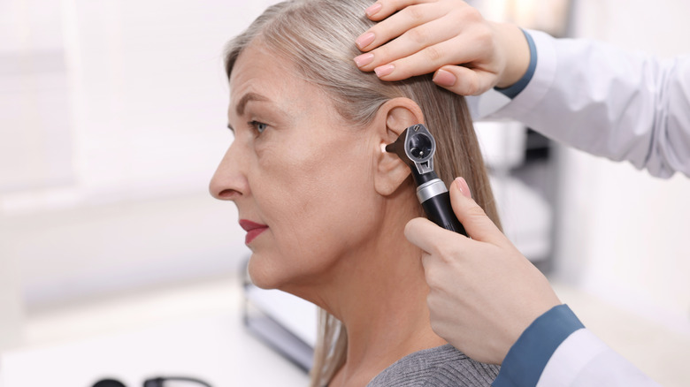 Doctor examining patient's ear with otoscope in clinic.