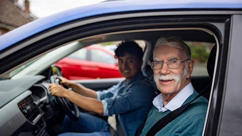 Young person at the wheel with an older person sitting on the passenger seat.