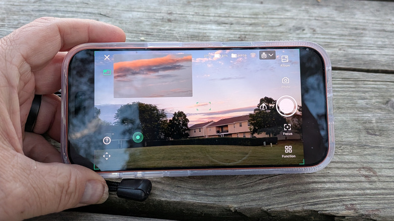 A man holding a phone with the telescope's viewfinder displayed.