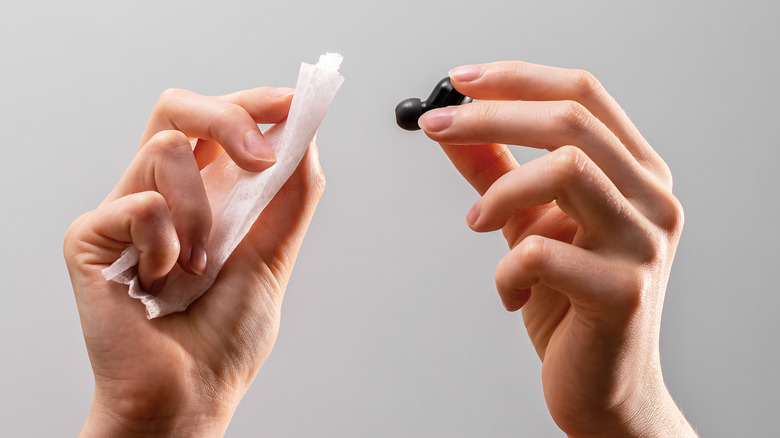 person holding wet wipes and earbuds