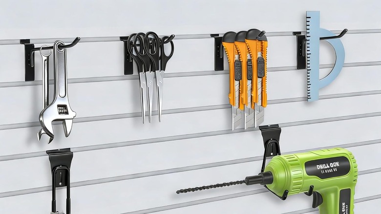 Wrench scissors, box cutter, measure, and drill hang on slat wall