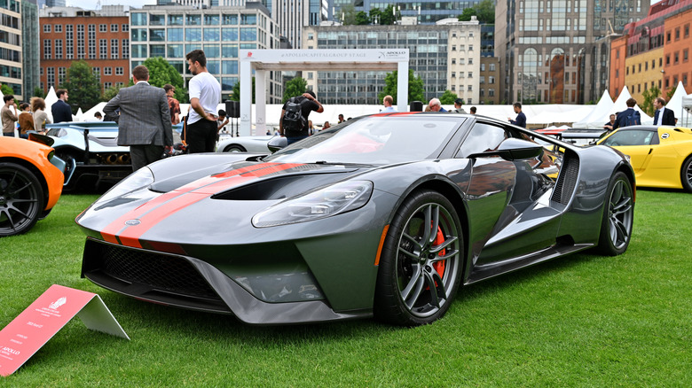 A Ford GT in gray with orange stripes at an open air car show, front 3/4 view