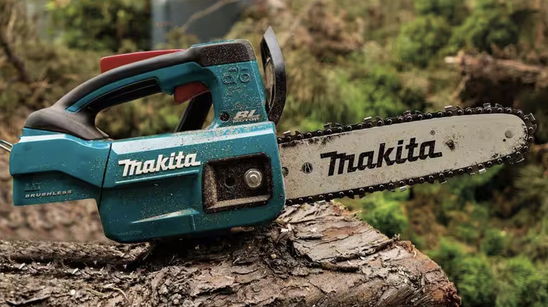 Used electric chainsaw sitting on fallen tree trunk