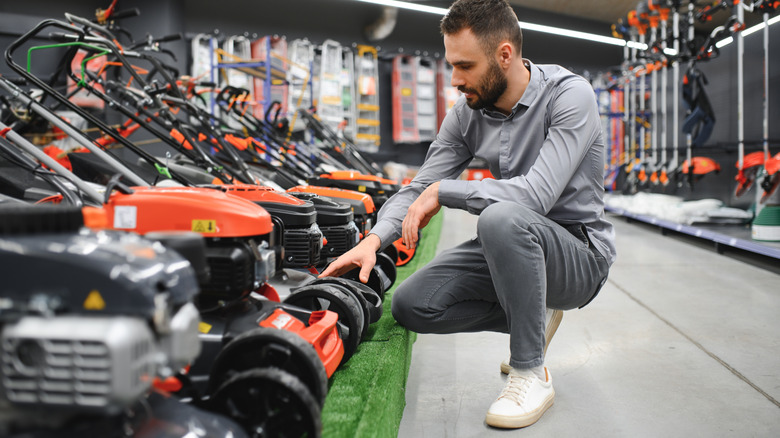 Man looking at lawn mowers in store