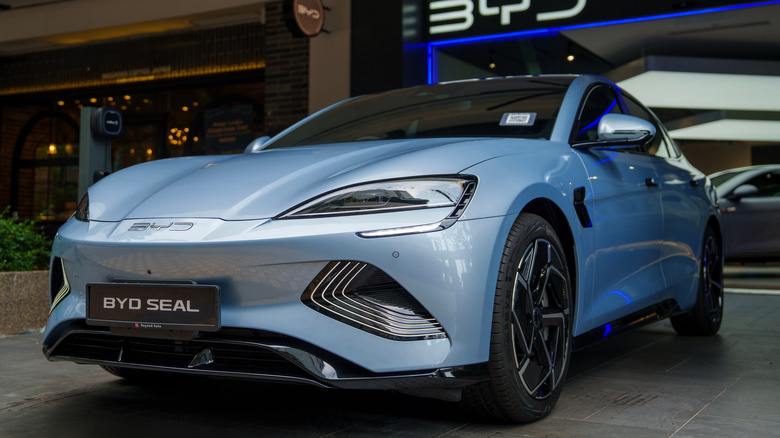 A light blue BYD Seal electric vehicle on display outside a BYD showroom,