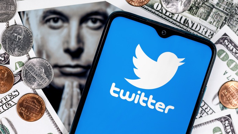 Twitter logo on a smartphone screen with Elon Musk's face in the background.