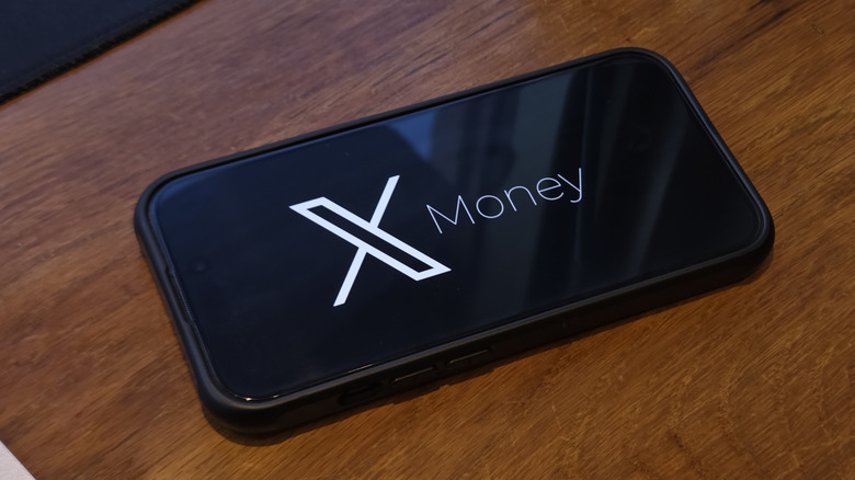 a phone on a table displaying the x money logo