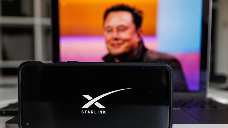 Silhouette of Elon Musk behind the Starlink UI on a phone.