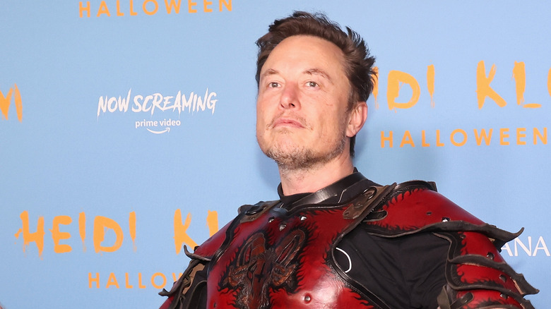 Elon Musk posing in a Halloween costume at an event.