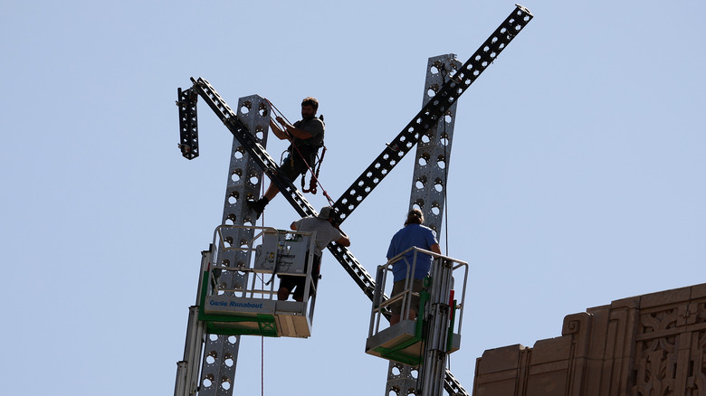 Workers dismantling X sign