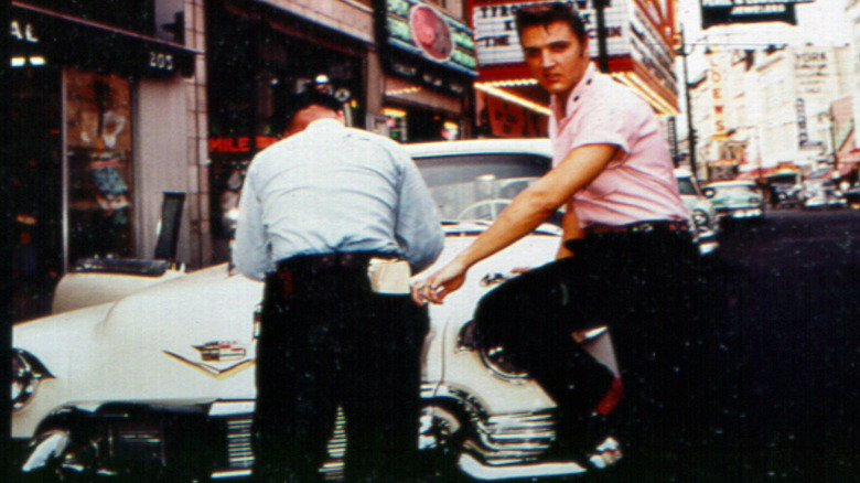 Elvis Presley leaning on a Cadillac