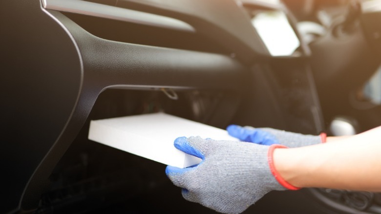 A person replacing a car's cabin air filter