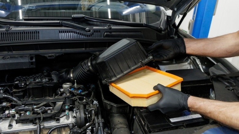 A person replacing a car's engine air filter