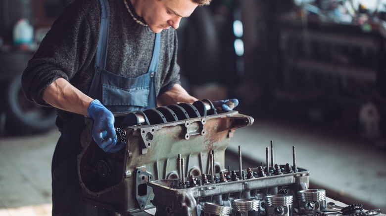 A man working on an engine on a work bench.