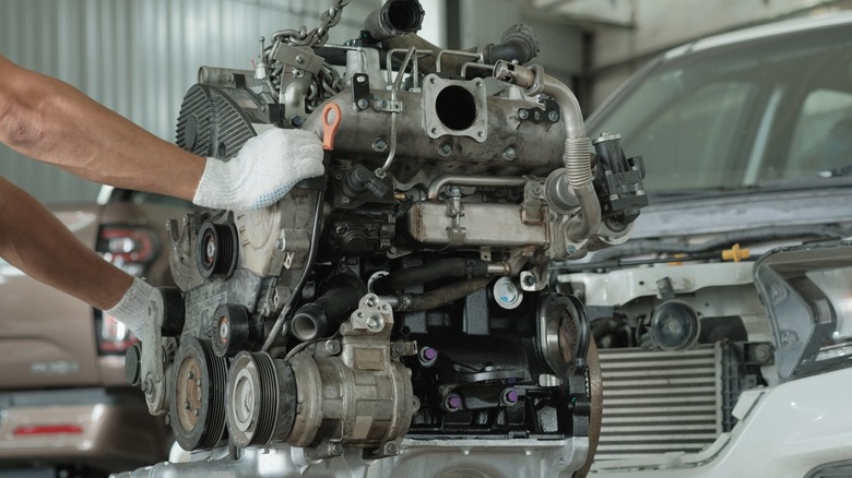 Mechanic holding engine that has been completely detached
