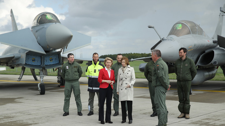 defense ministers stand next to eurofighter typhoon and dassault rafale