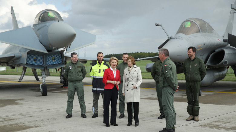 German and French leaders, along with military personnel, standing in front of fighter planes