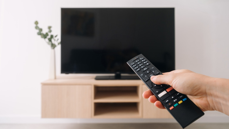 Person using a remote to turn on a TV