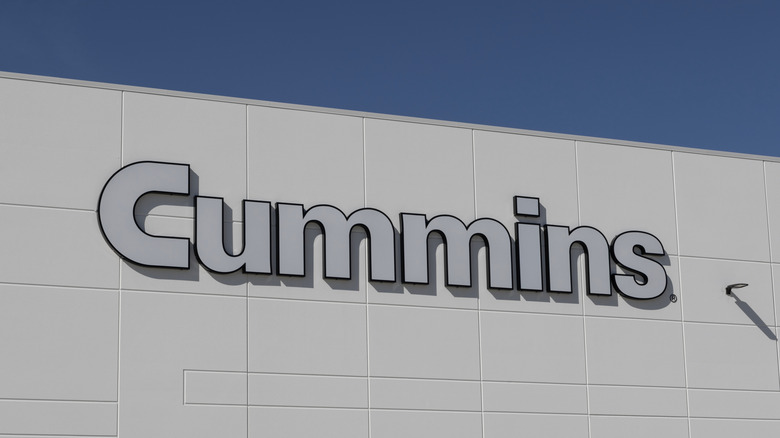 A white building with the Cummins logo on it in silver typesetting, against a clear afternoon sky.