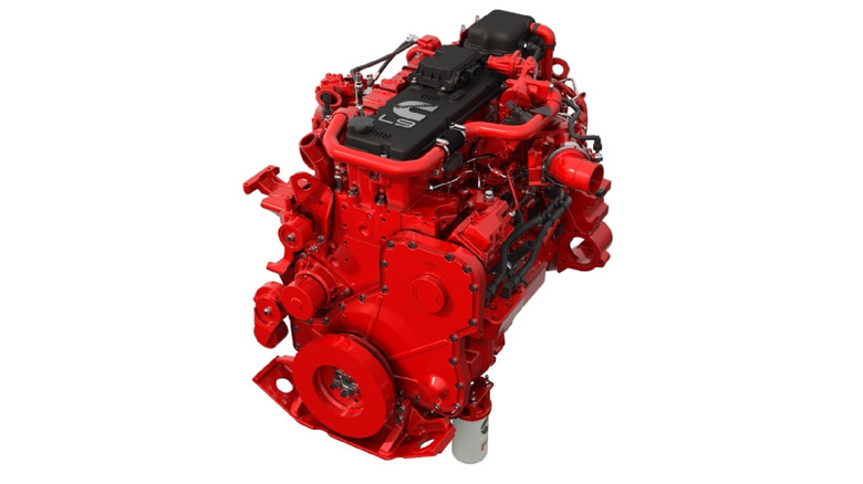 Cummins L9 engine in signature red finish, displayed against a white background, with black valve cover, visible turbocharger piping, and front accessory mounts.