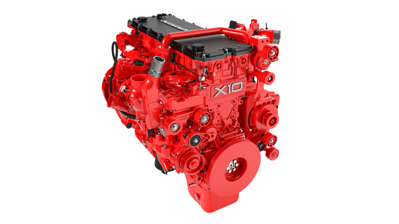Cummins X10 engine in striking red with black dual valve covers, exposed belt drive system, and compact turbocharger