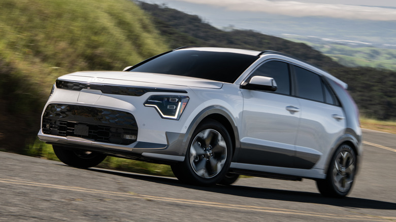 Front 3/4 view of white Kia Niro EV with gray details on hilly road