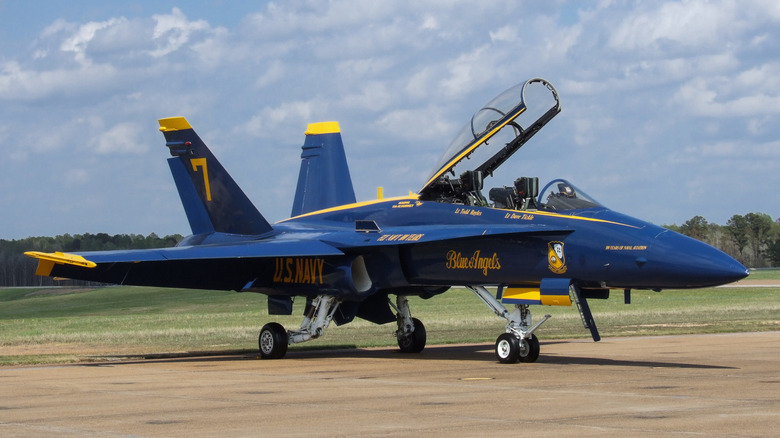 McDonnell Douglas F/A-18 Hornet fighter jet in Blue Angels colors seen from front right parked on tarmac with the canopy open