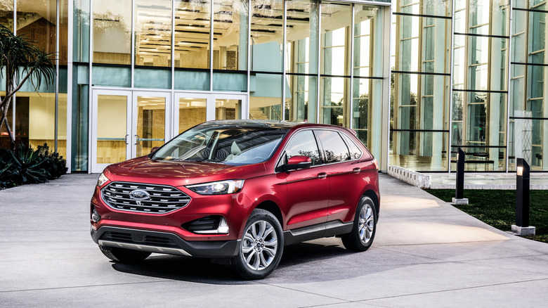 Red 2019 Ford Edge Titanium seen from front left parked in front of a modern building