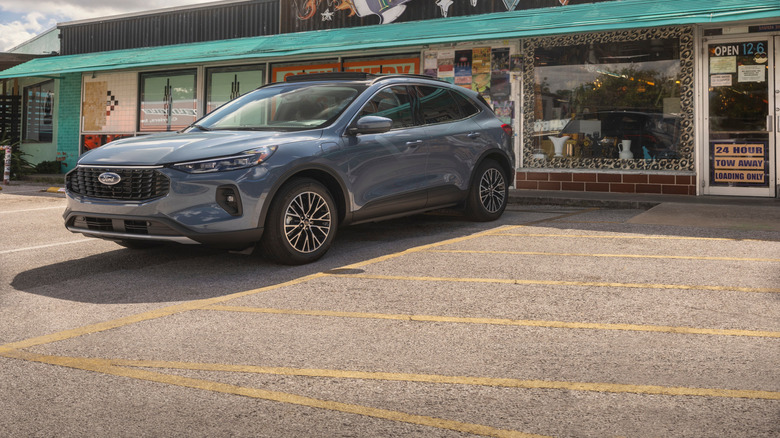 Blue 2025 Ford Escape Platinum Edition SUV seen parked in front of a vintage-looking motel