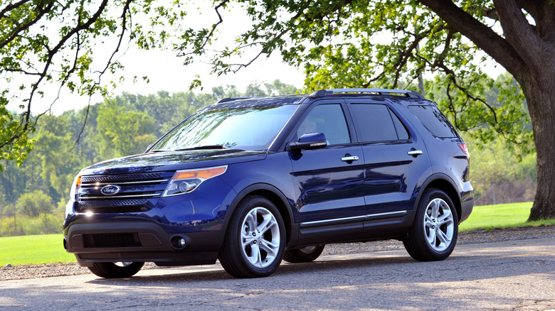 Blue 2012 Ford Explorer seen from left front parked under a tree
