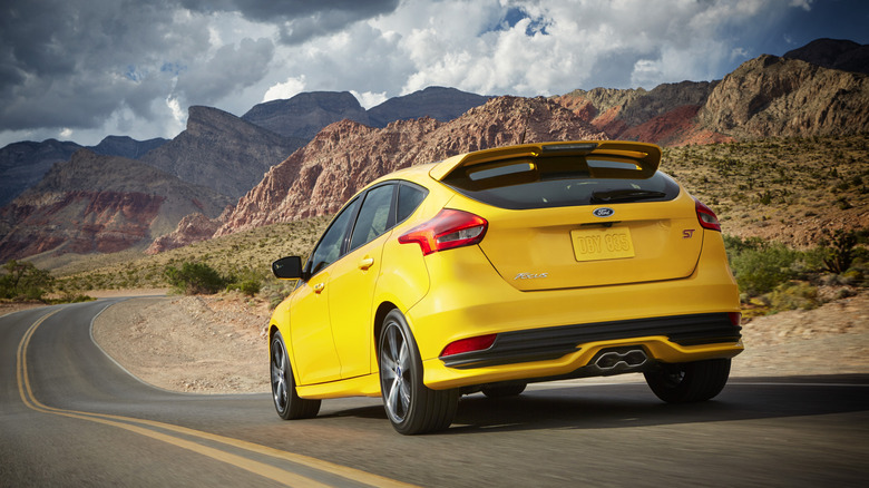 Yellow 2018 Ford Focus ST hatchback seen from left rear on a desert highway
