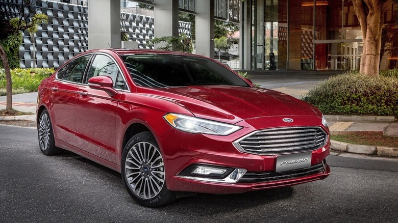 Red 2017 Ford Fusion seen from right front parked by hotel entrance