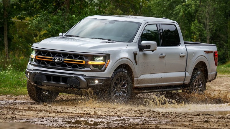 Ford F-150 Tremor driving in mud with trees in the background