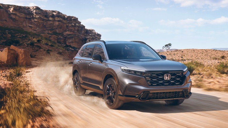A dark grey sixth generation CR-V driving on a dirt road.