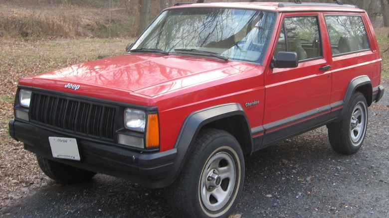 A red Jeep Cherokee parked near some trees