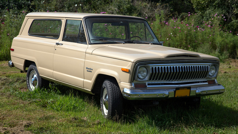 A beige first generation Jeep Cherokee parked in grass