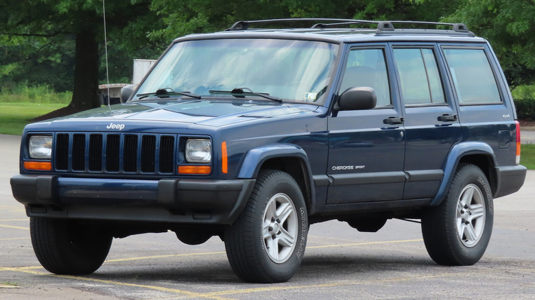 A blue Jeep Cherokee sitting in a parking spot