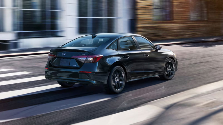 A black Honda Civic driving down a city street