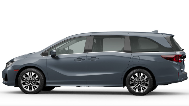 A red Honda Odyssey driving next to a lake on a highway