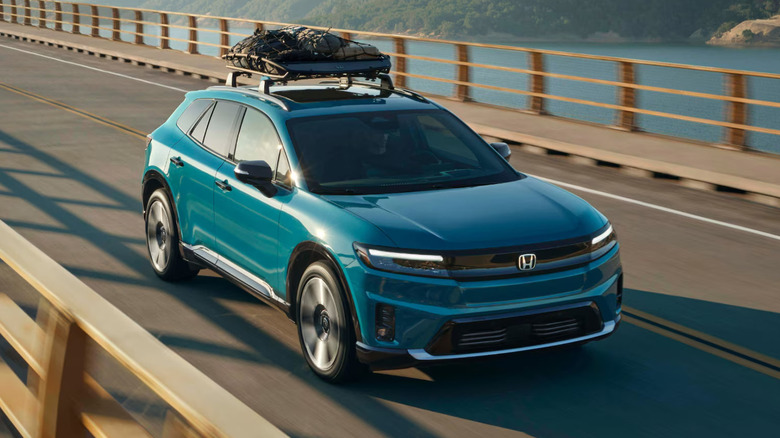 A teal Honda Prologue driving on a bridge over a lake