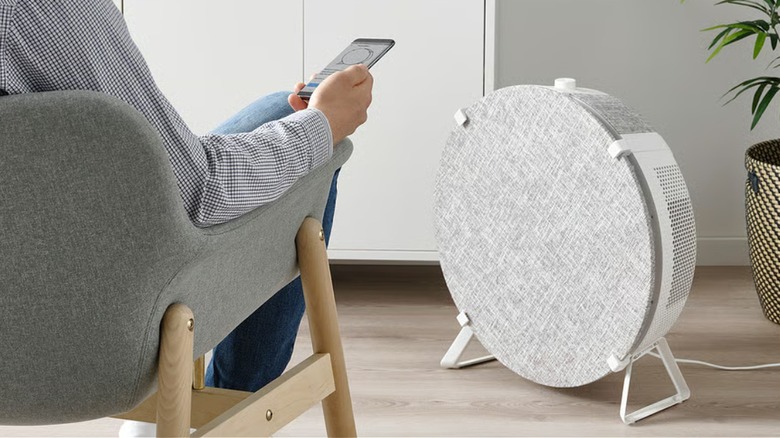 Air purifier placed on floor in front of a sitting man