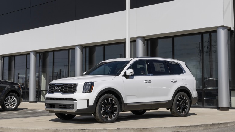 White Kia Telluride in front of a Kia dealership