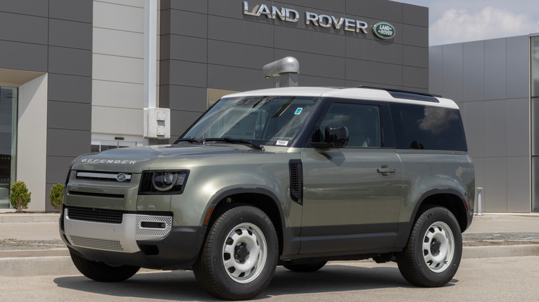 A grey-green Defender 90 S on display outside a dealership in the afternoon