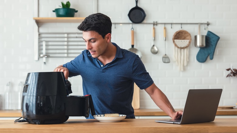 Man using Air Fryer and laptop 