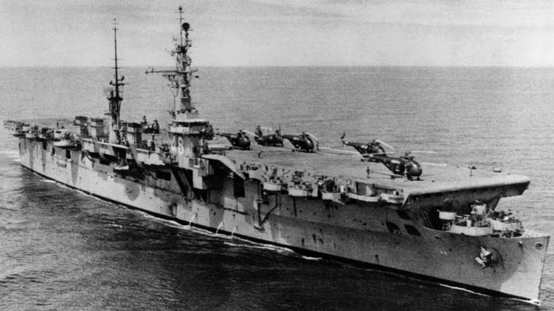 The USS Saipan underway at sea with helicopters loaded onto its flight deck in 1955